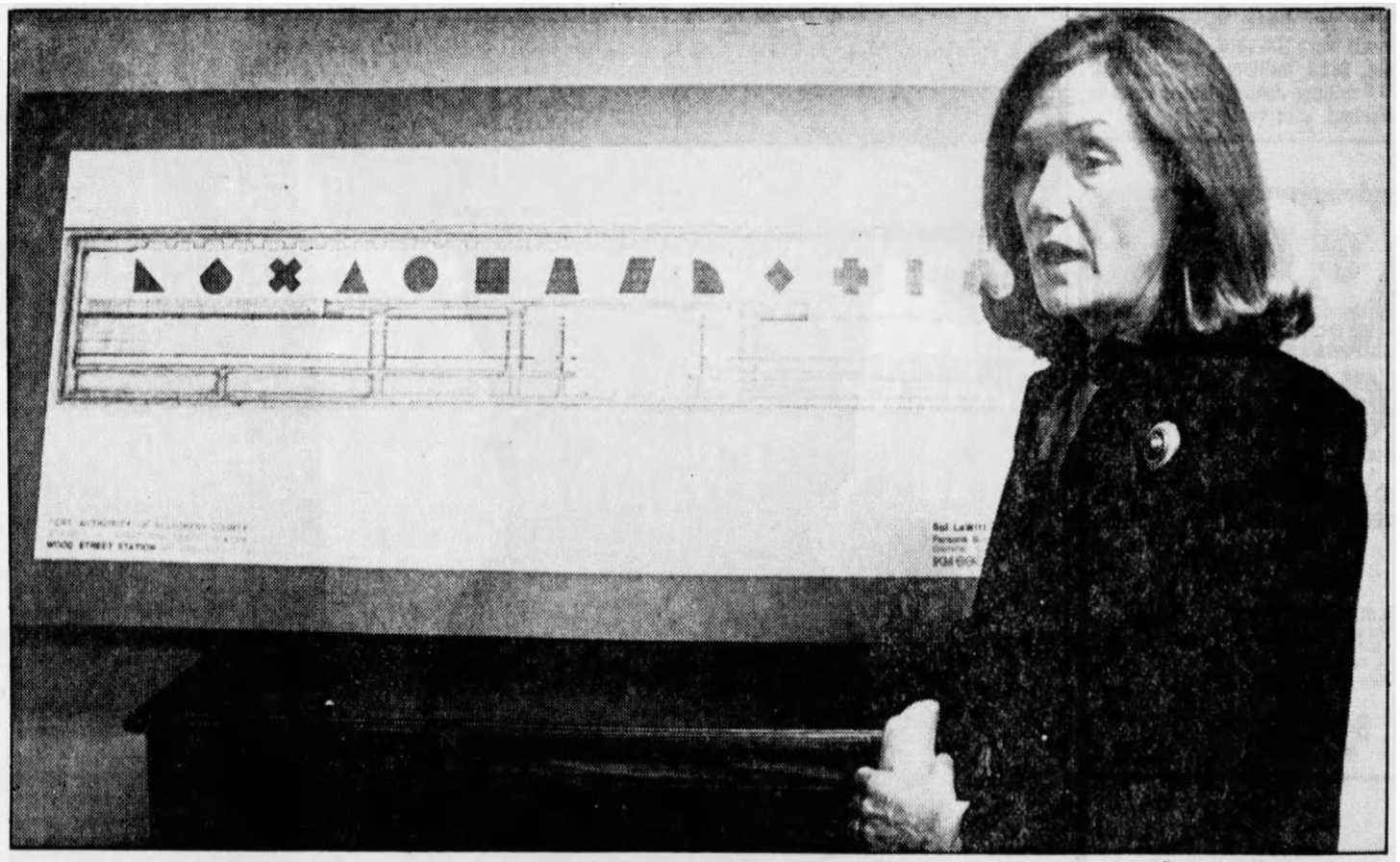 Photo of Carol Brown, chairperson for the Committee on Arts for the Light Rail Transit System, showcasing the draft plan of Sol LeWitt's installation entitled 