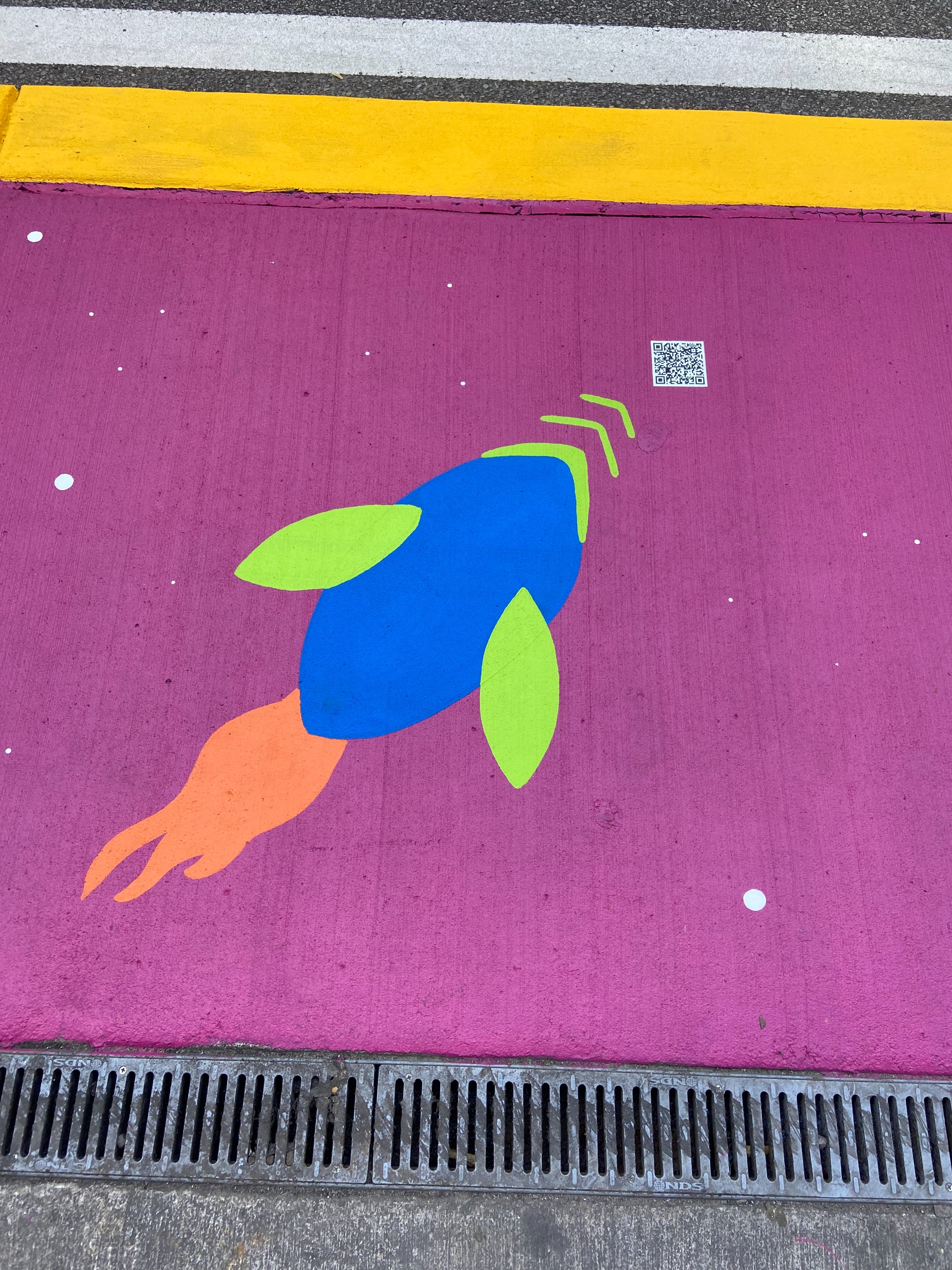 A purple painted sidewalk with a blue and green rocketship