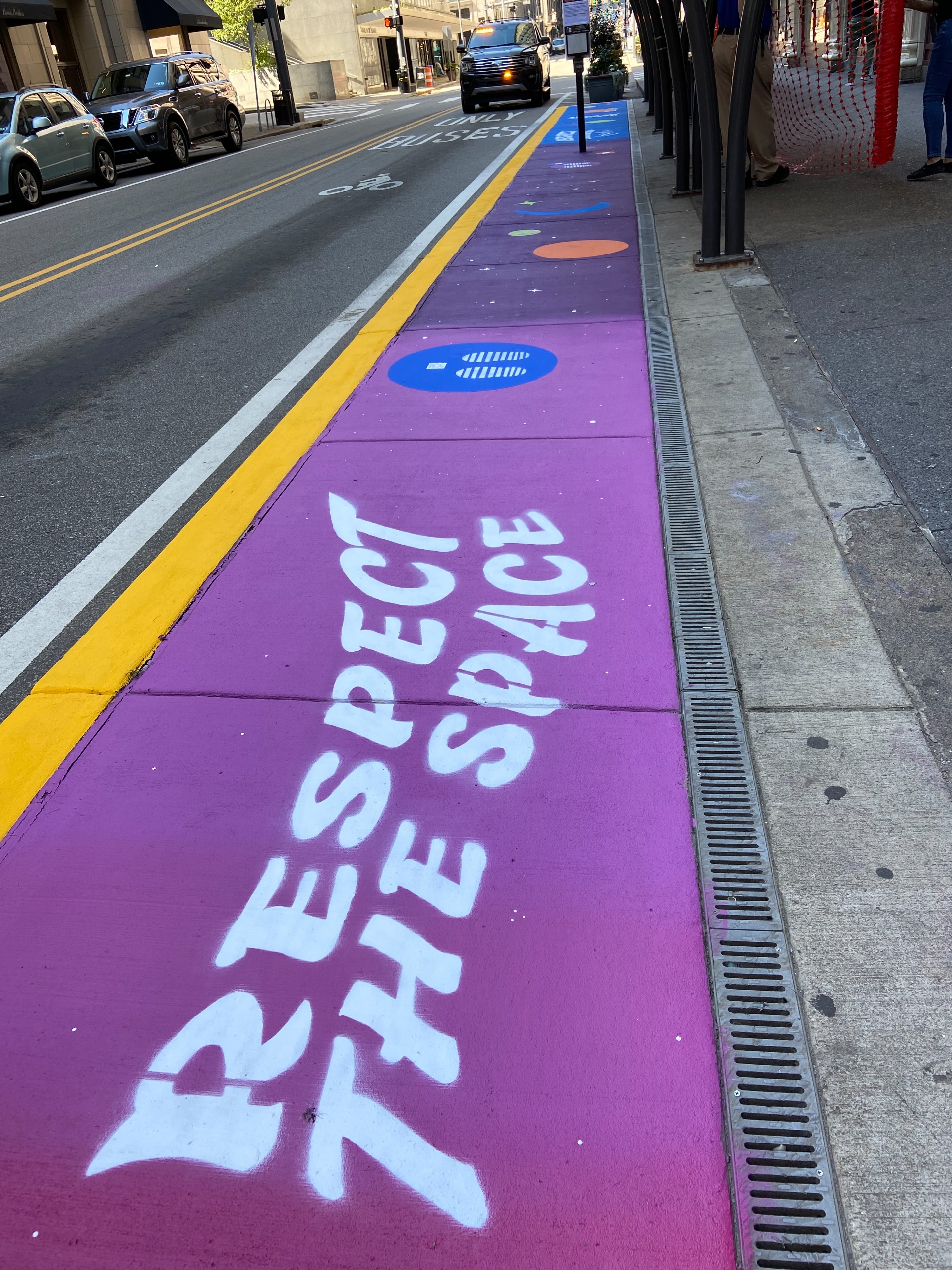 Photograph of a sidewalk painted purple with the text 